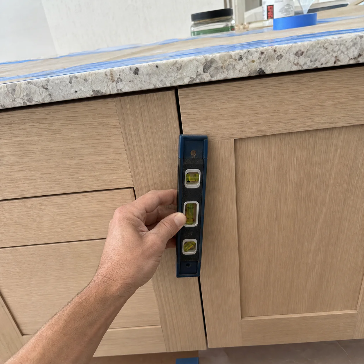 Remodeler checking an even reveal on new white-oak cabinetry