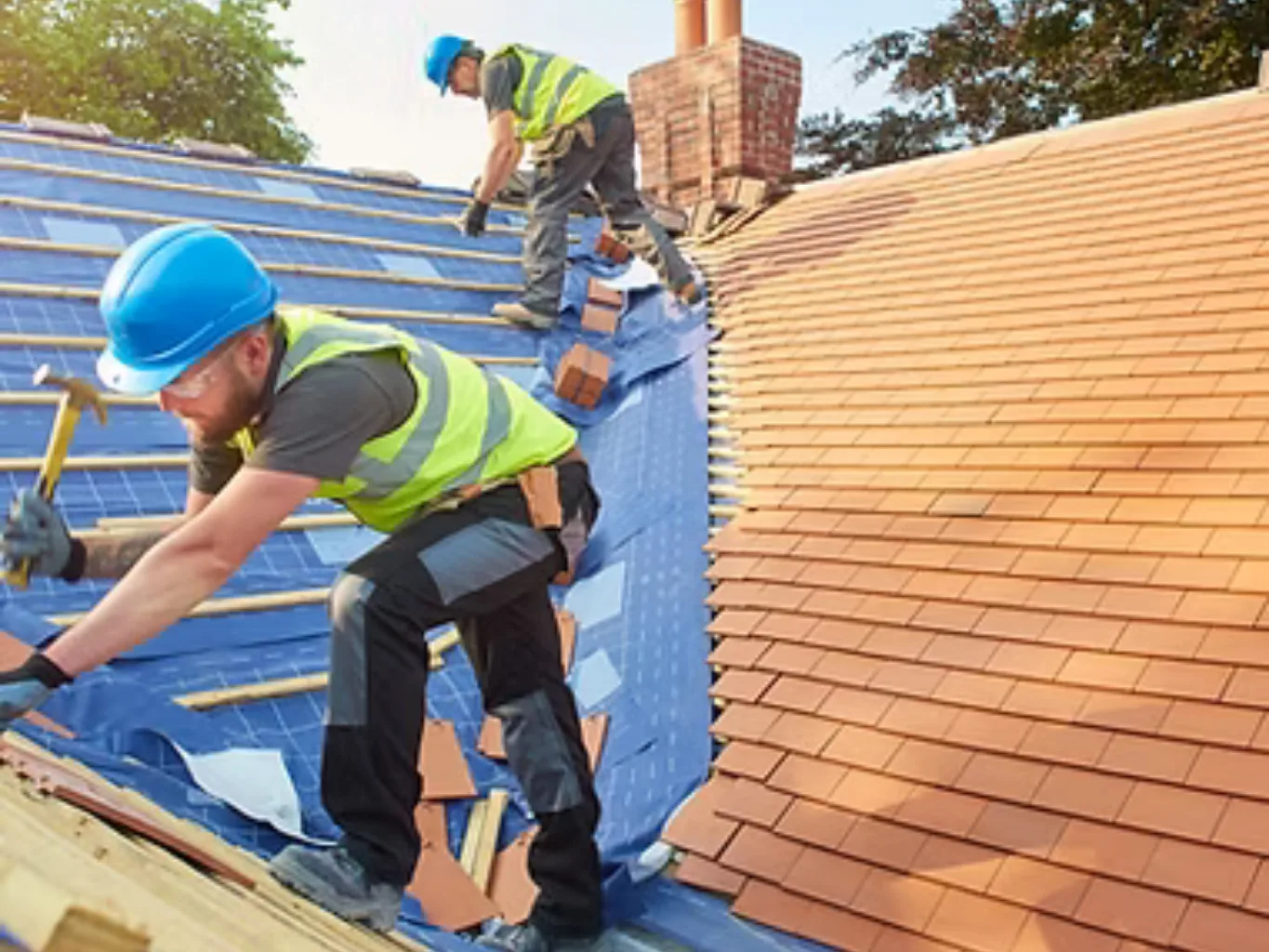A home remodeling contractor working on a residential roofing job — mid-task, hands, tools and the work itself in sharp focus, the rest of the space softly out of focus
