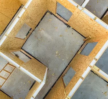 A home remodeling contractor working on a residential framing job — mid-task, hands, tools and the work itself in sharp focus, the rest of the space softly out of focus