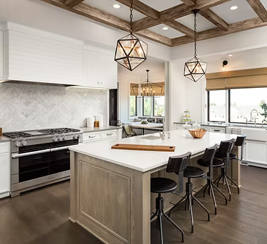 A home remodeling contractor working on a residential kitchen remodeling job — mid-task, hands, tools and the work itself in sharp focus, the rest of the space softly out of focus